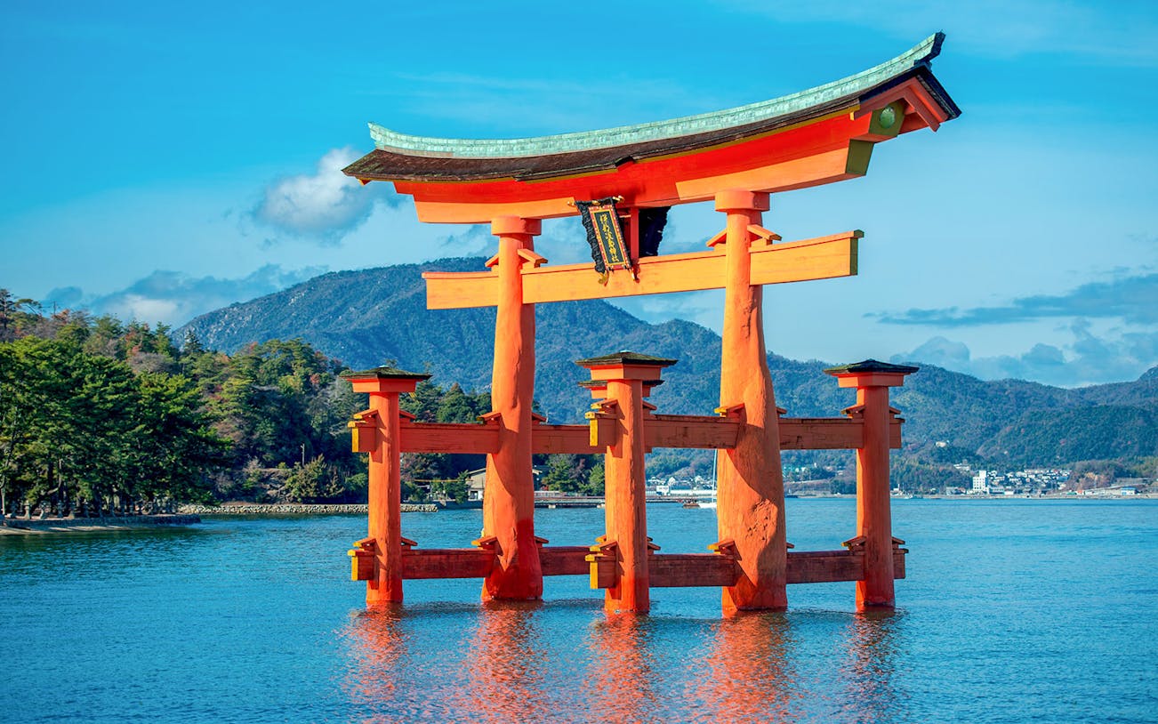 Torii gate at Itsukushima Shrine, Miyajima, Japan, with mountains in the background.