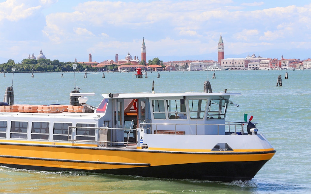 Ferry boat on the water with Venice skyline in the background.