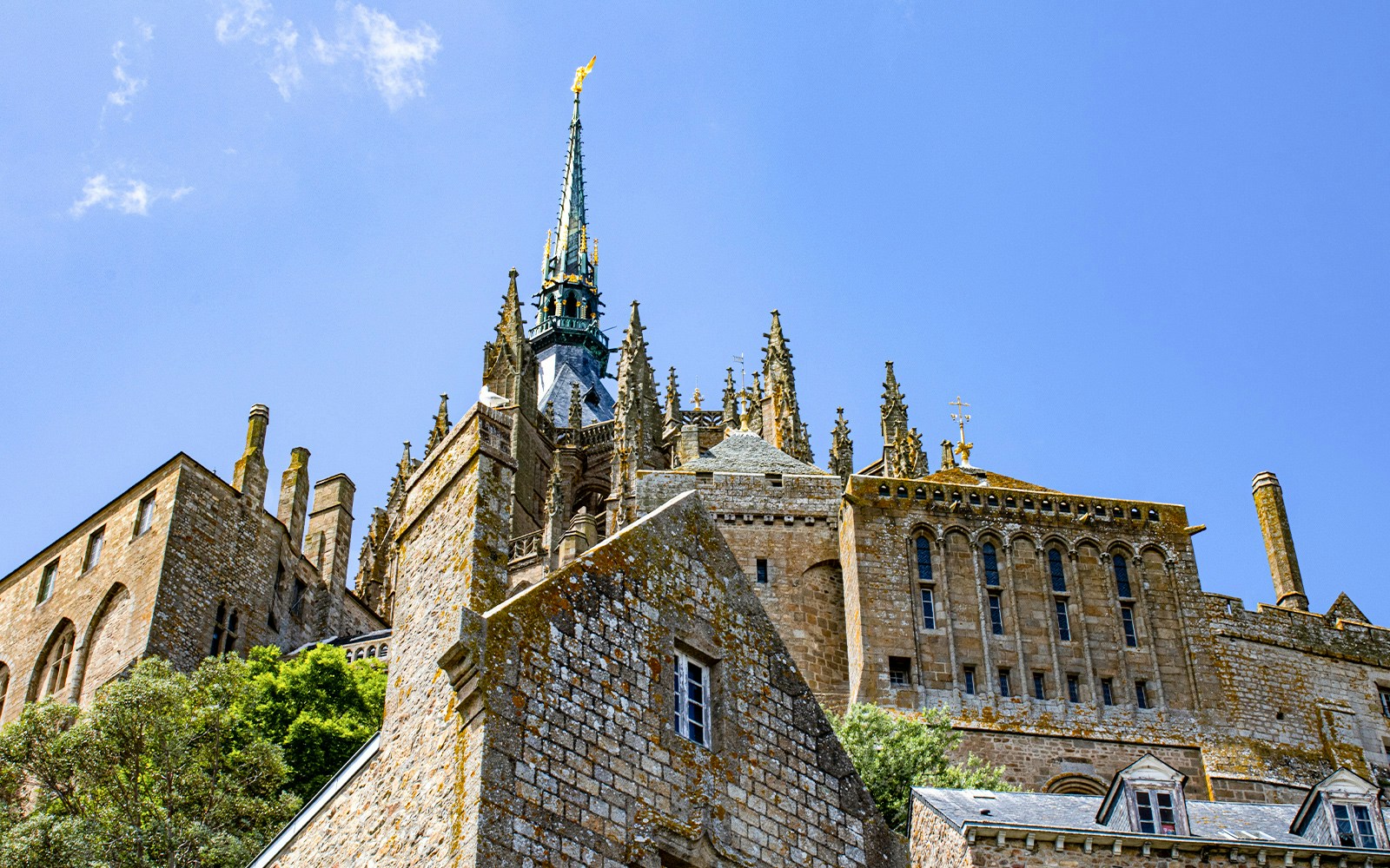 Mont Saint Michel abbey spire and stone architecture under blue sky, Normandy, France.
