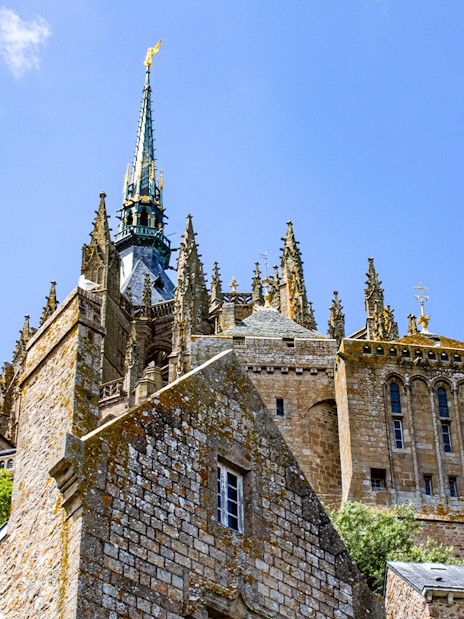 Mont Saint Michel abbey spire and stone architecture under blue sky, Normandy, France.