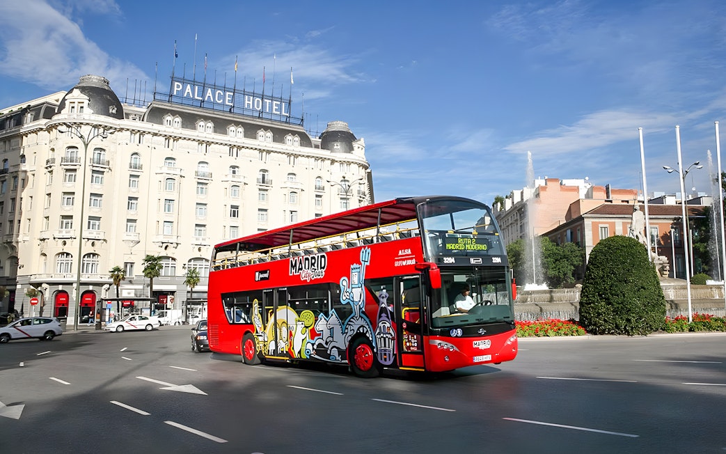 Red Madrid hop-on hop-off bus near Palace Hotel and fountain.