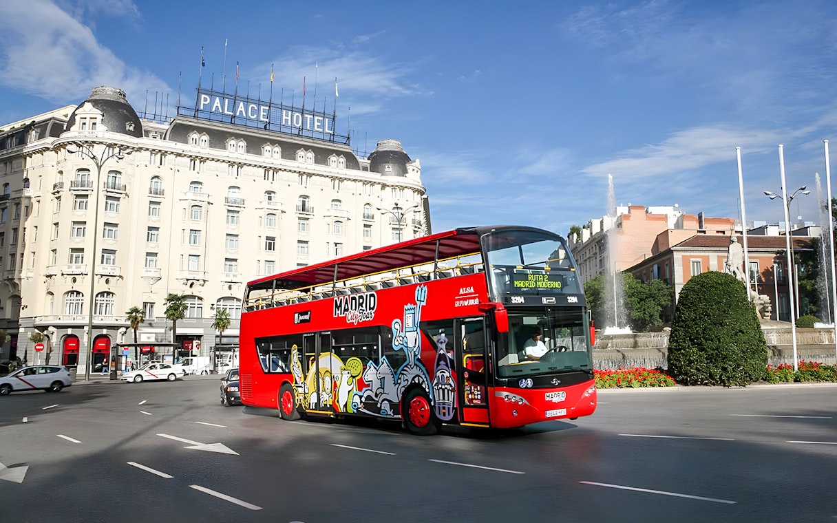 Red Madrid hop-on hop-off bus near Palace Hotel and fountain.