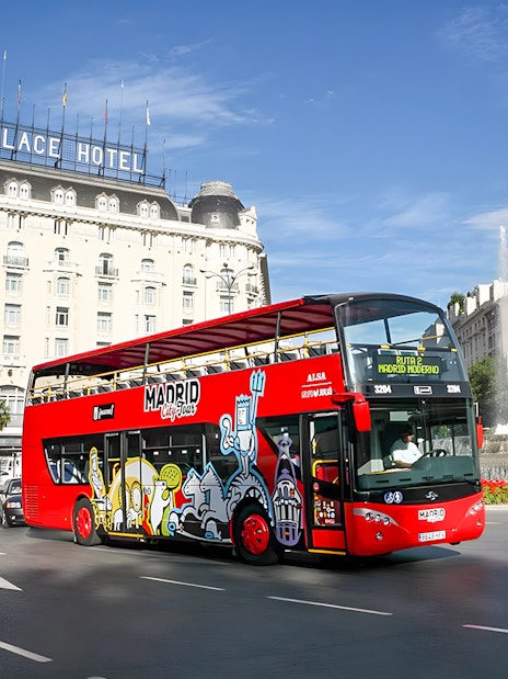 Red Madrid hop-on hop-off bus near Palace Hotel and fountain.