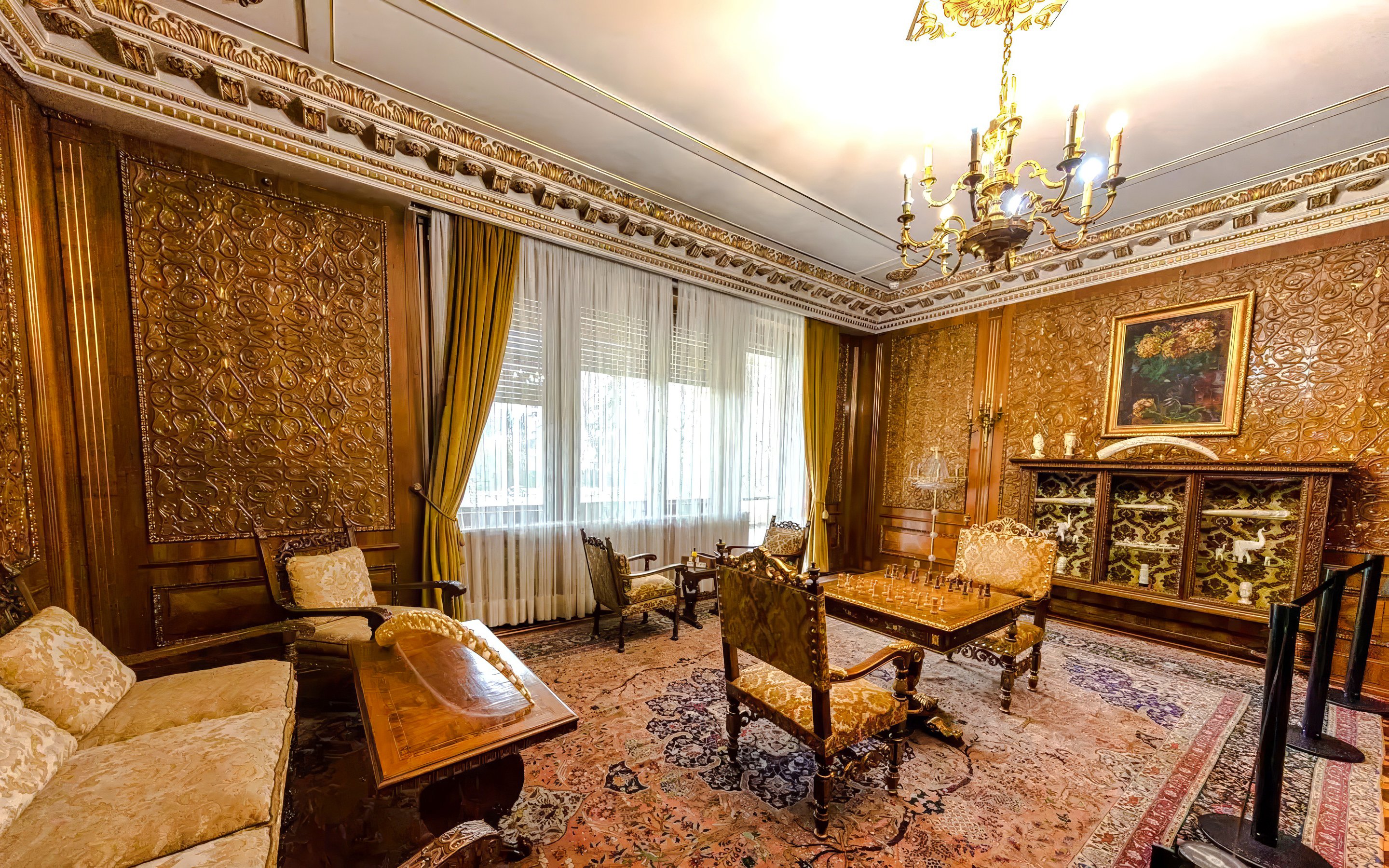 Luxurious room with ornate wood paneling and chandelier inside Ceausescu Mansion.