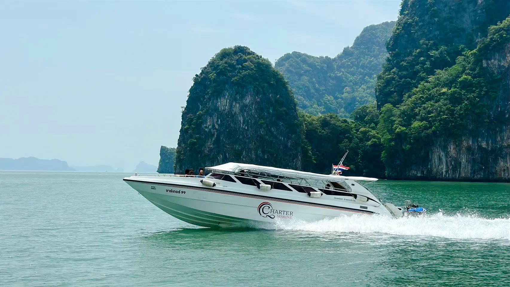 Speedboat cruising near limestone cliffs in Phang Nga Bay, Phuket.