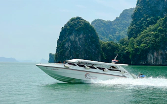 Speedboat cruising near limestone cliffs in Phang Nga Bay, Phuket.