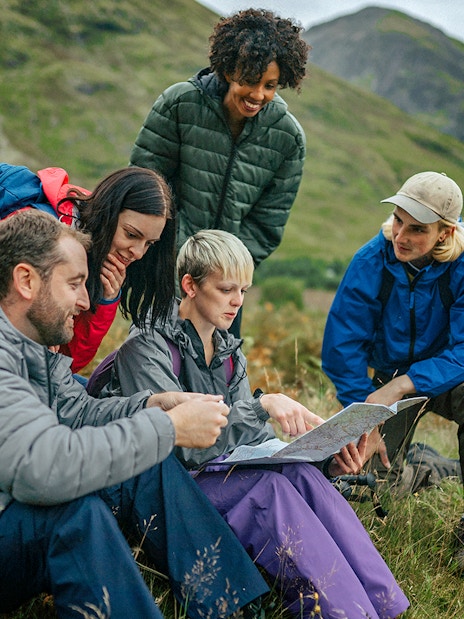 Tour guide explaining map to tourists in a scenic mountain landscape.