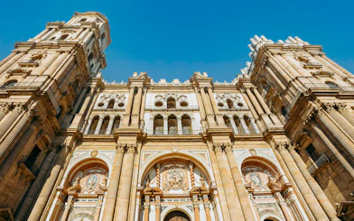 Málaga Cathedral facade with detailed architecture under a clear blue sky.