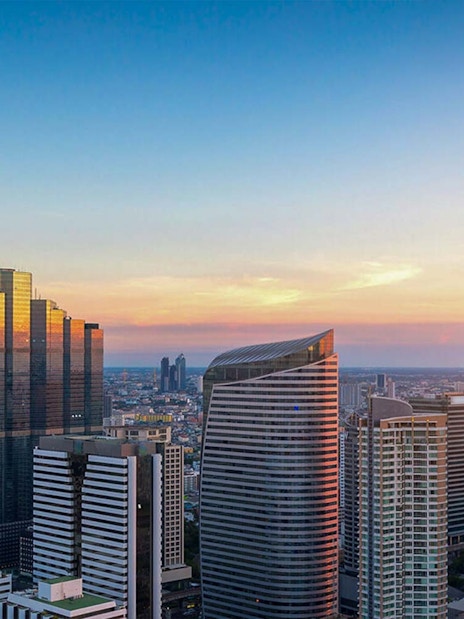 Mahanakhon SkyWalk view of Bangkok skyline at sunset.
