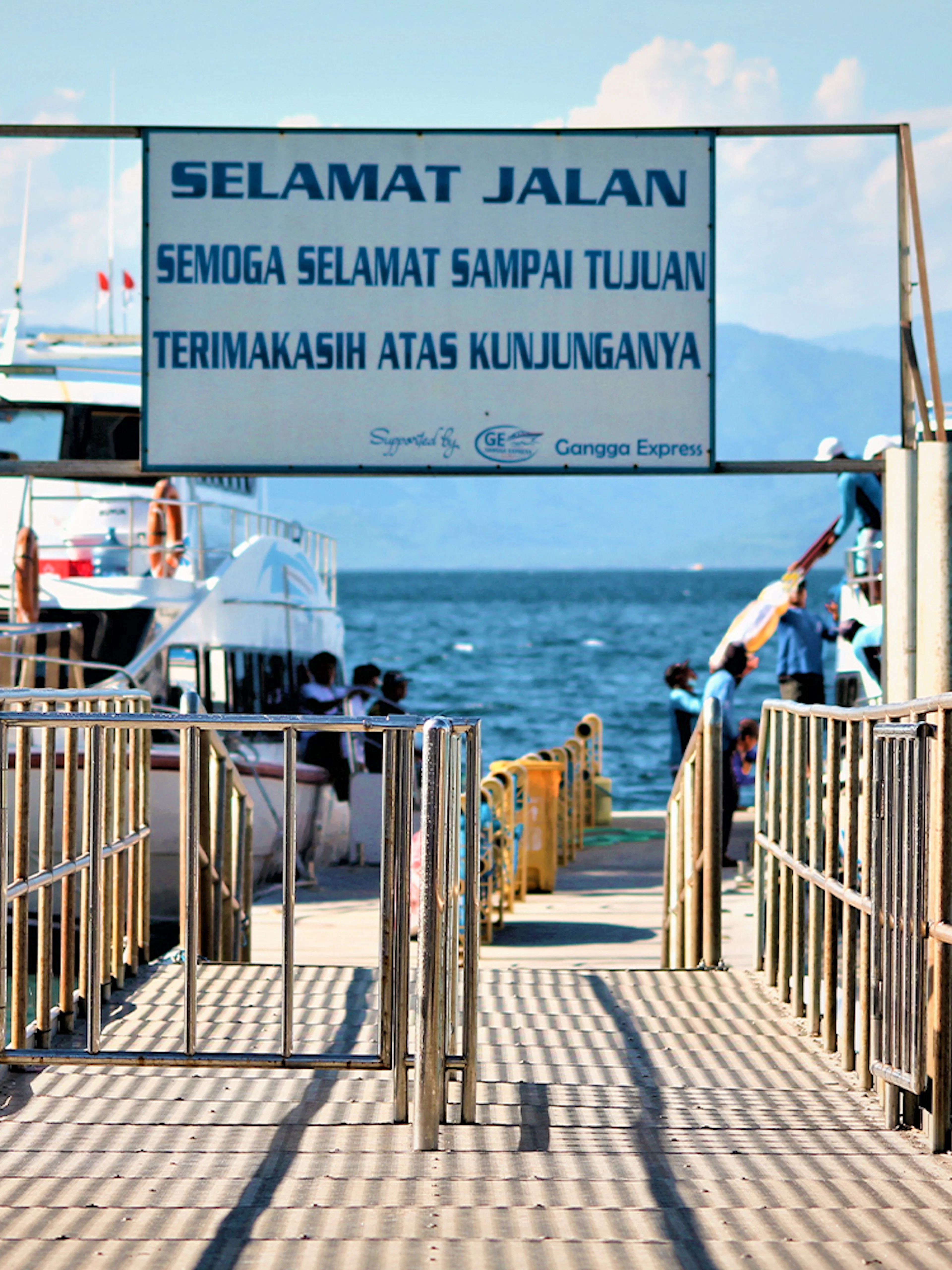 Ferries docked at Nusa Penida island pier with passengers boarding.