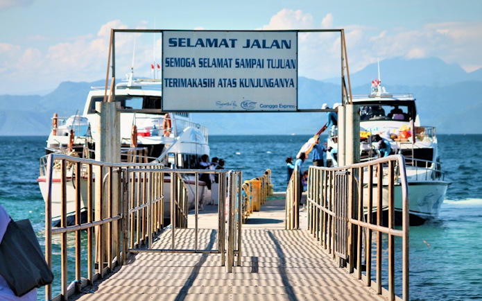 Ferries docked at Nusa Penida island pier with passengers boarding.