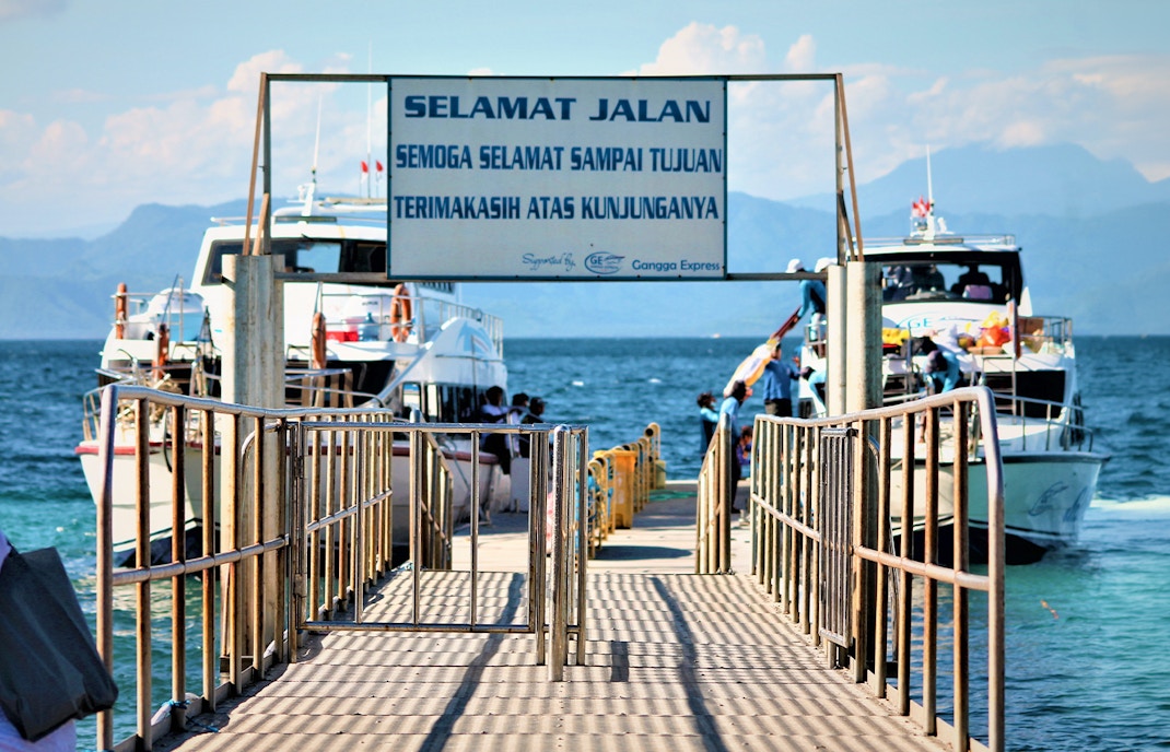 Ferries docked at Nusa Penida island pier with passengers boarding.