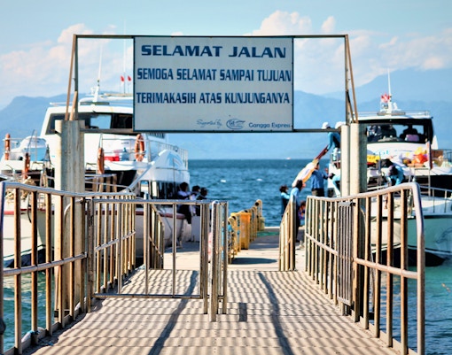 Ferries docked at Nusa Penida island pier with passengers boarding.