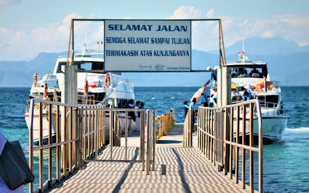 Ferries docked at Nusa Penida island pier with passengers boarding.