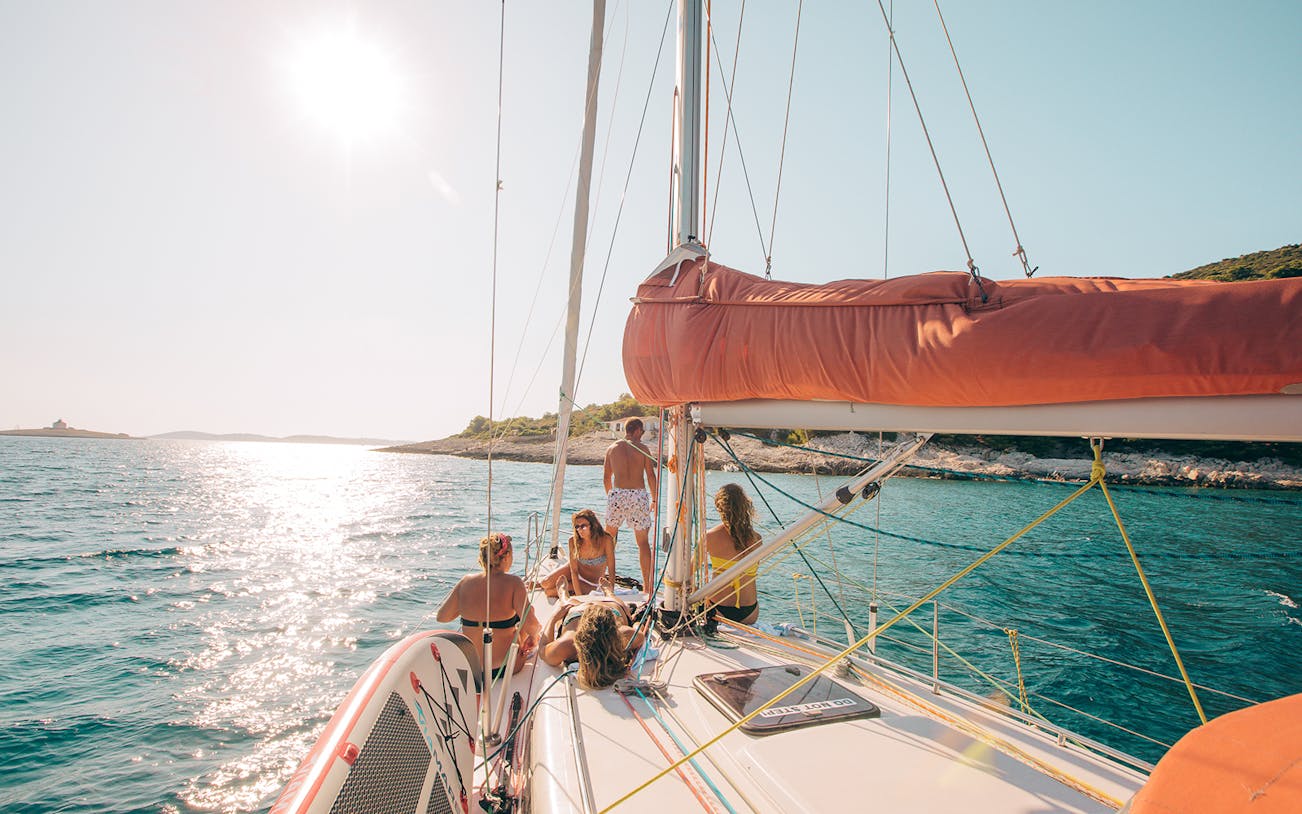 Sailing yacht with people relaxing near Hvar and Pakleni Islands.
