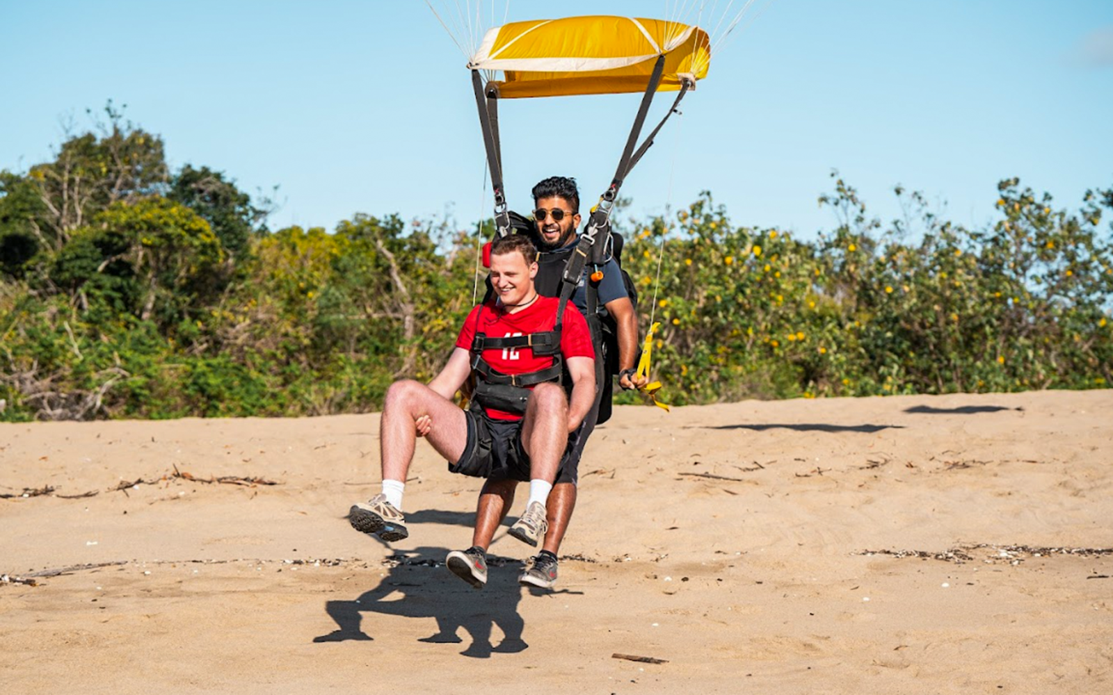 Tandem skydive landing on Airlie Beach with parachute in background.