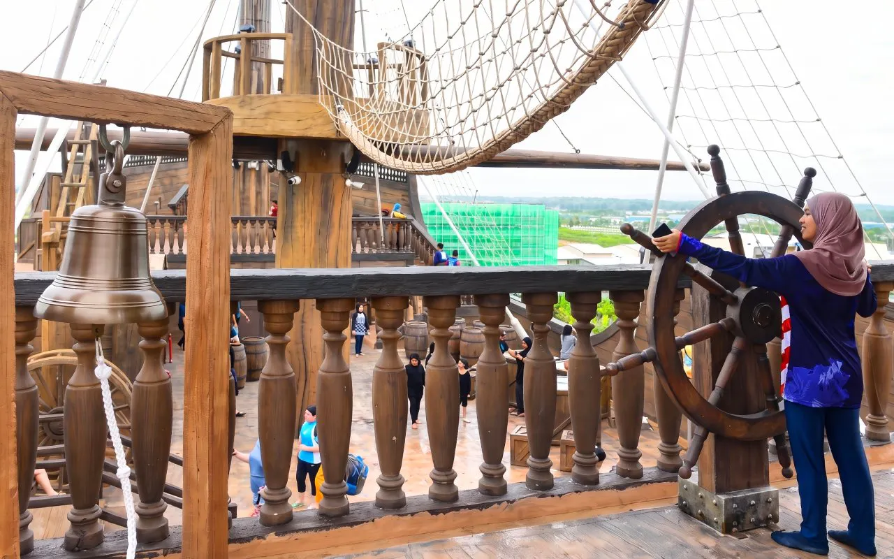 Person steering ship wheel at SplashMania Waterpark, Kuala Lumpur, Malaysia.