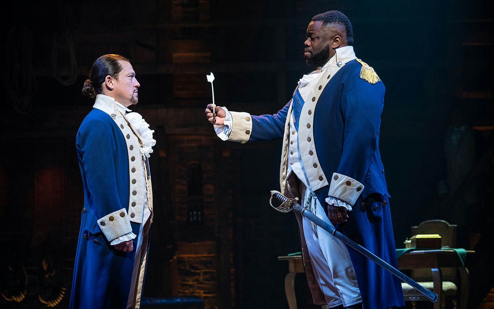 Two actors in colonial costumes perform a scene from the musical Hamilton.