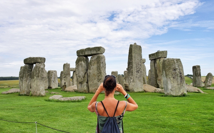 Woman photographing Stonehenge in Wiltshire, England.