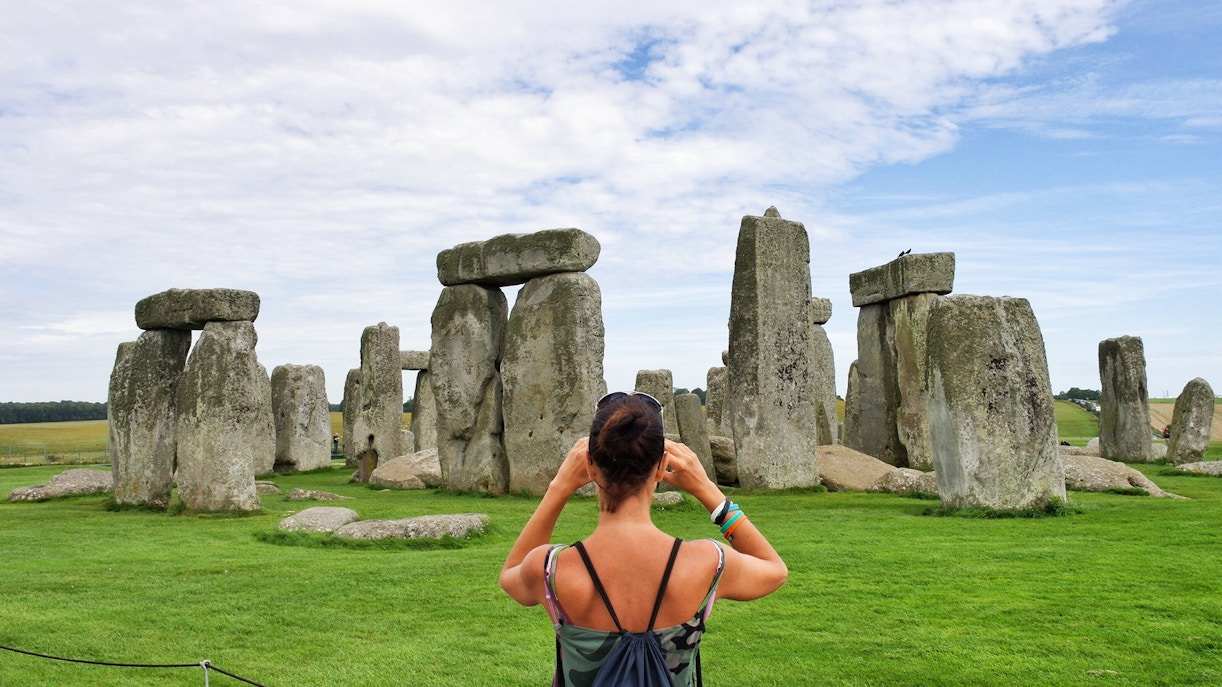 Woman photographing Stonehenge in Wiltshire, England.