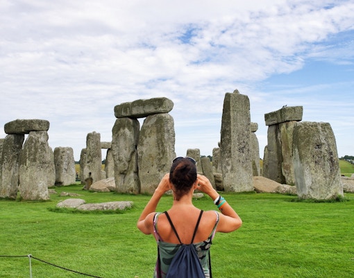 Woman photographing Stonehenge in Wiltshire, England.