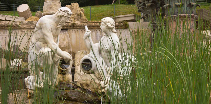 Statues in Schönbrunn Palace Garden fountain surrounded by greenery.