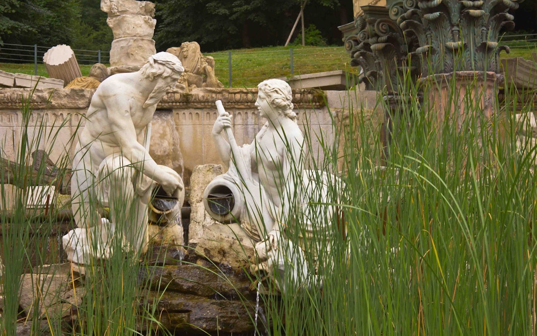 Schönbrunn Palace Garden ruins with classical statues and lush greenery in Vienna, Austria.
