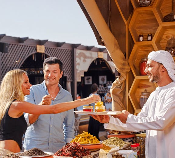 Guests sampling spices and honey at a market during a desert safari experience.