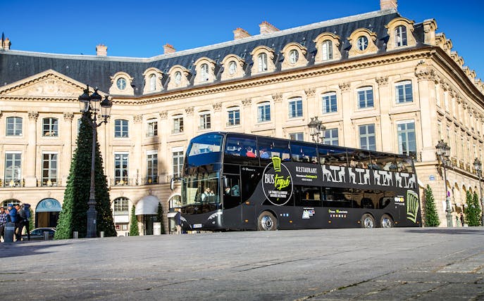 Bus Toqué Paris driving past historic Parisian architecture.