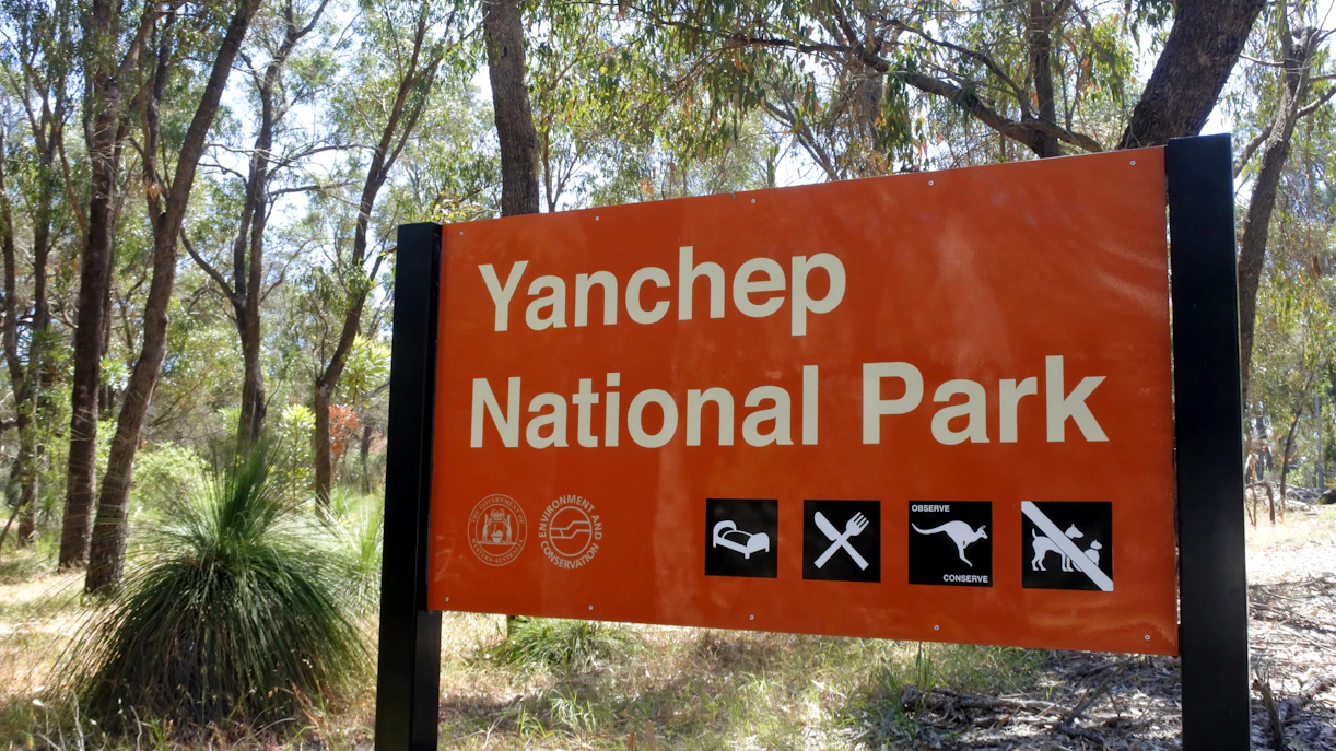 Yanchep National Park entrance sign surrounded by trees.
