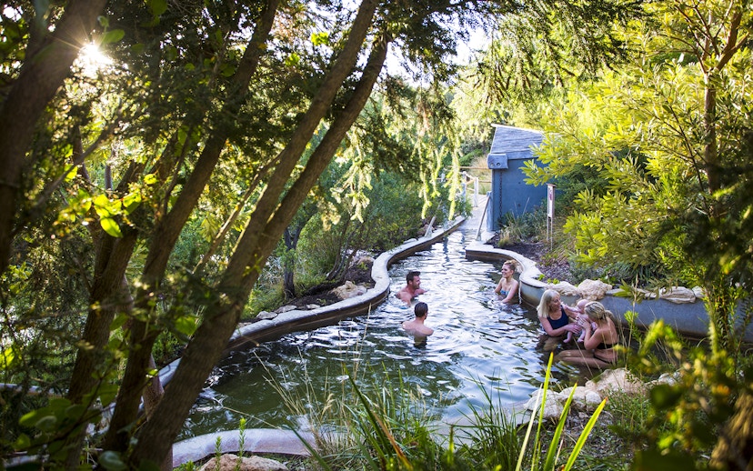 Families enjoying natural thermal pools at Peninsula Hot Springs surrounded by lush greenery.