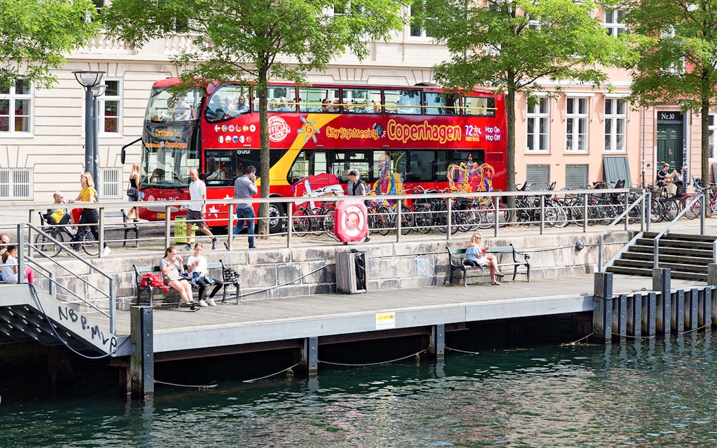 Hop-On-Hop-Off bus by canal in Copenhagen with people on the promenade.