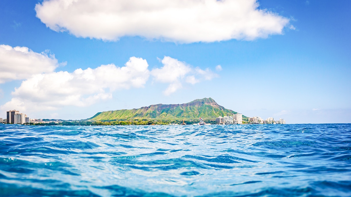 Diamond Head volcano and Honolulu skyline viewed from ocean surface.