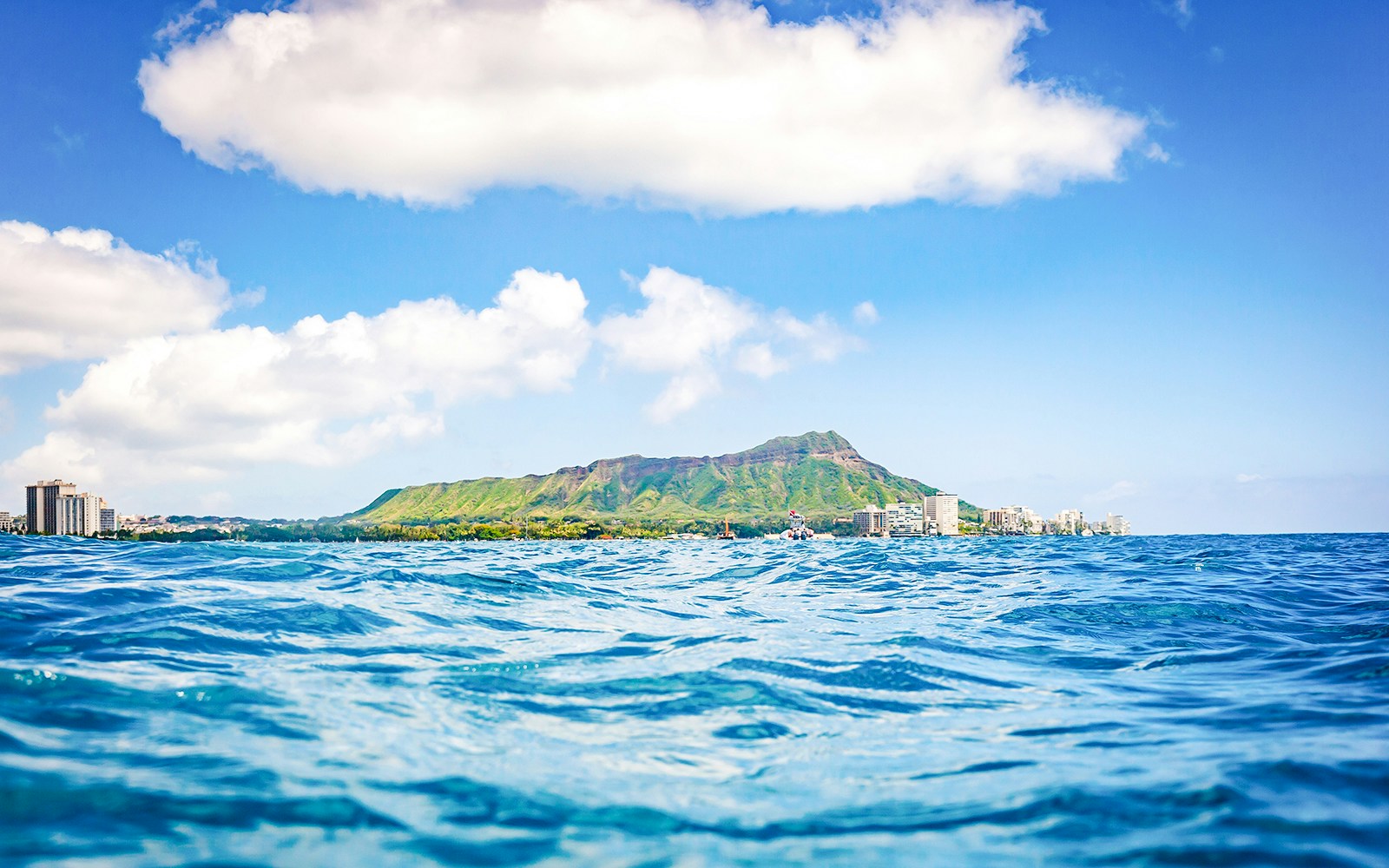 Diamond Head volcano and Honolulu skyline viewed from ocean surface.