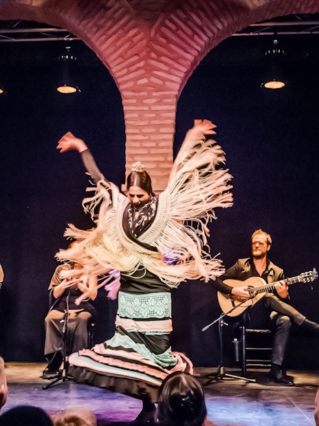 Flamenco dancer performing at Dance Museum with musicians in the background.