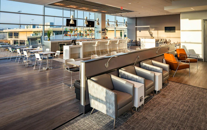 Aspire Lounge seating area with bar and tables at San Diego International Airport.