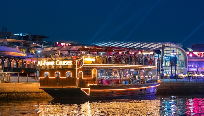 Luxury dhow cruise on Dubai Canal with illuminated cityscape in the background.
