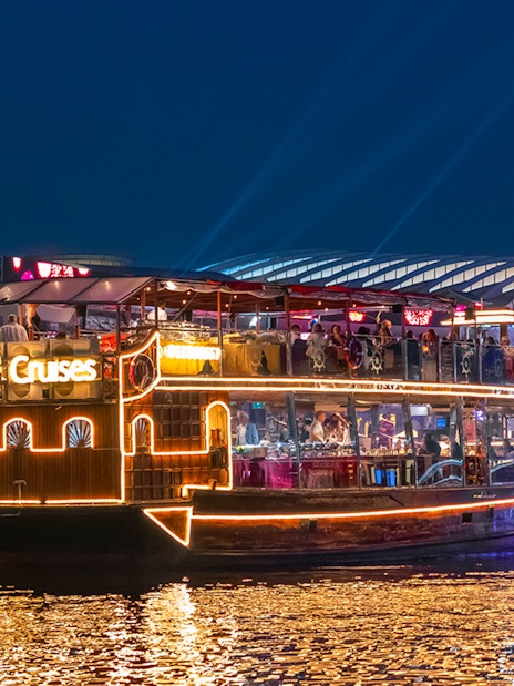 Luxury dhow cruise on Dubai Canal with illuminated cityscape in the background.