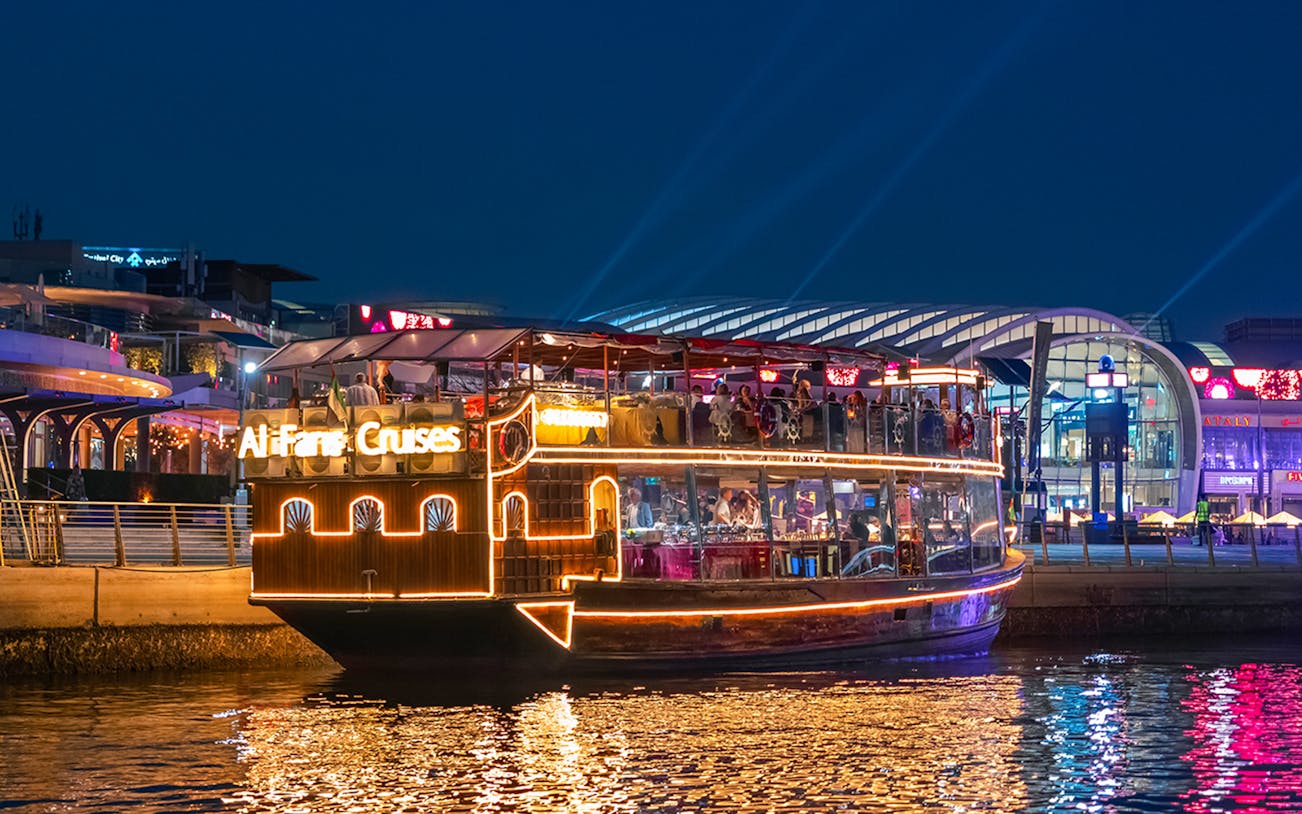 Luxury dhow cruise on Dubai Canal with illuminated cityscape in the background.