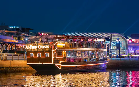 Luxury dhow cruise on Dubai Canal with illuminated cityscape in the background.