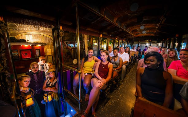 Tourists on a Ghosts & Gravestones trolley tour with actors in spooky costumes.