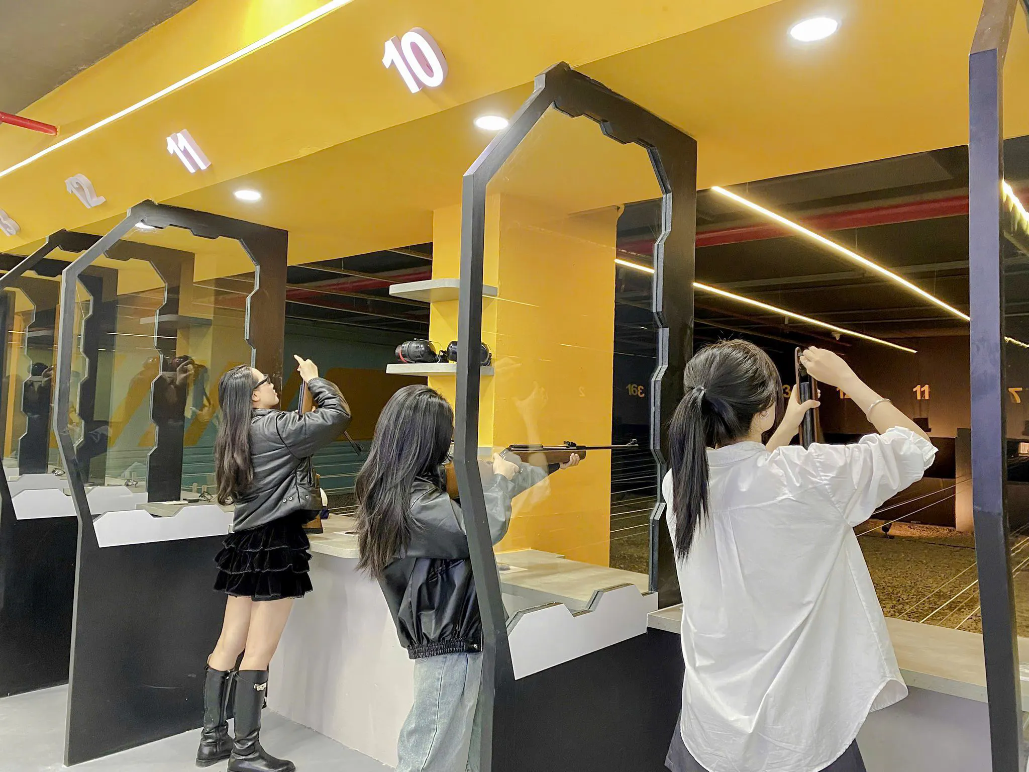 Participants aiming rifles at an indoor shooting range in Sa Pa with instructor guidance.