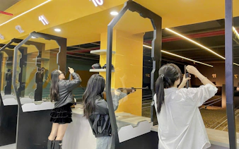 Participants aiming rifles at an indoor shooting range in Sa Pa with instructor guidance.
