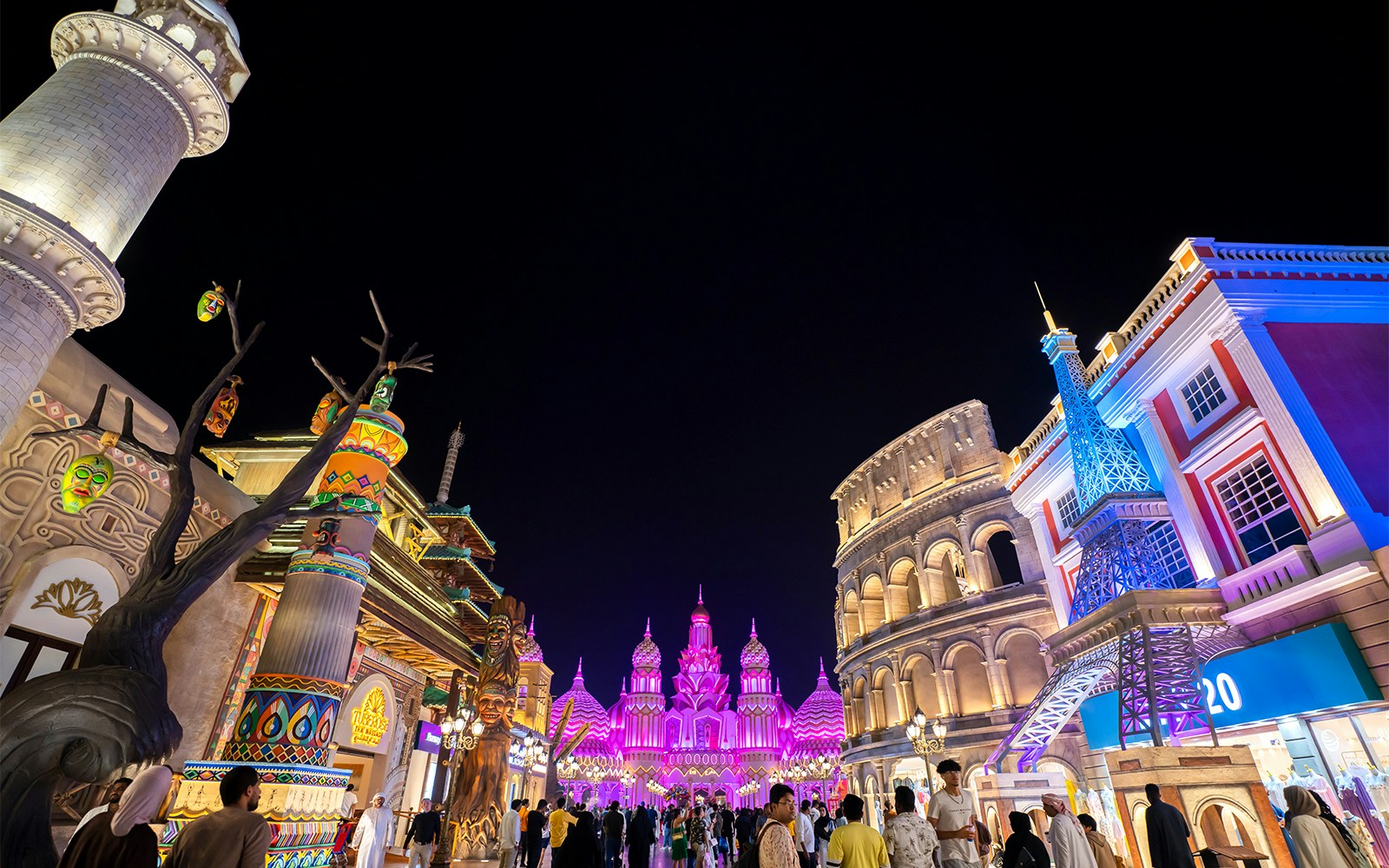 Pathway in Global Village at night with illuminated cultural landmarks and vibrant architecture.