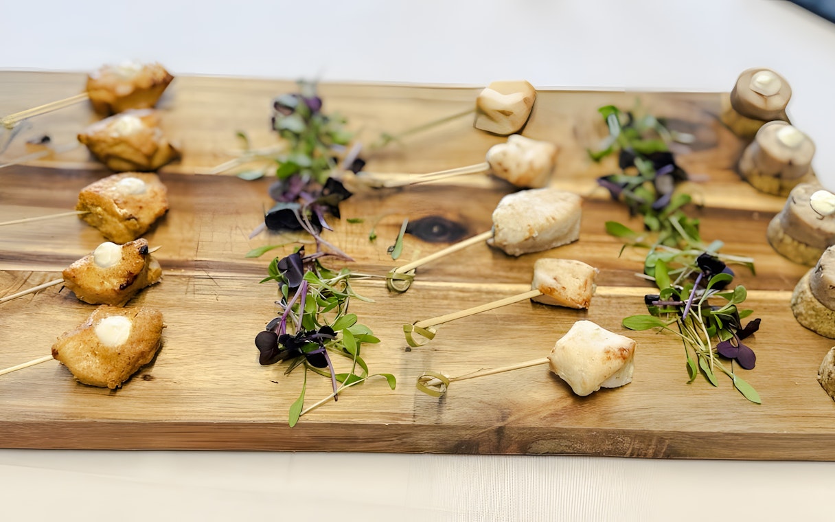Professional catering platter with skewered appetizers and microgreens.