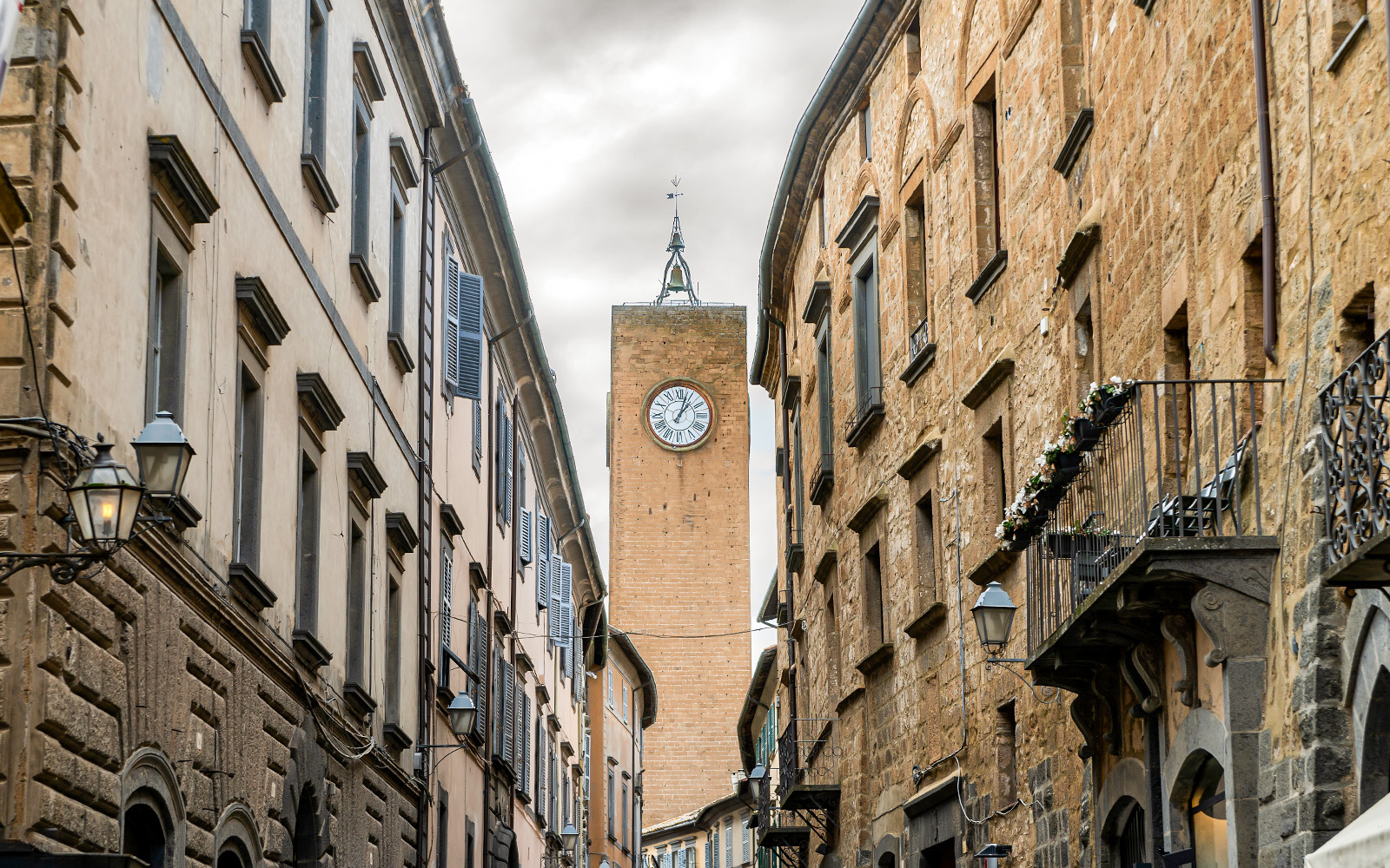 Clock tower between narrow stone buildings in Orvieto, Italy.