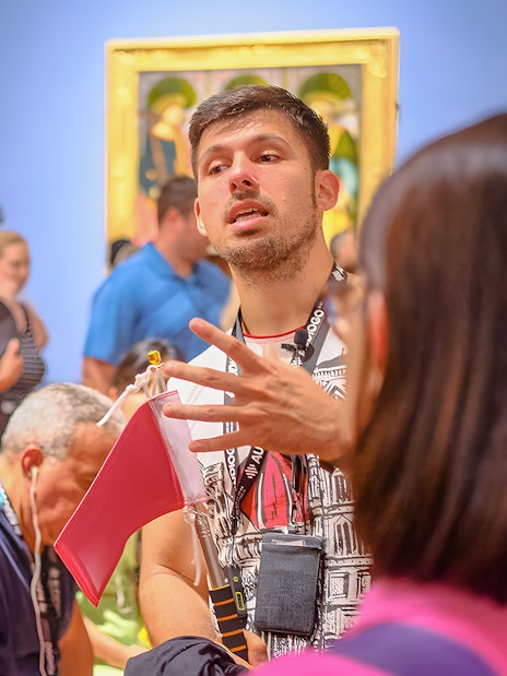 Guide explaining artwork to tourists at Accademia Gallery, Florence.