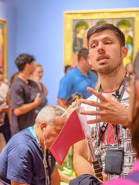 Guide explaining artwork to tourists at Accademia Gallery, Florence.