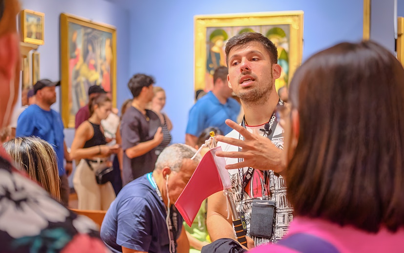 Guide explaining artwork to tourists at Accademia Gallery, Florence.