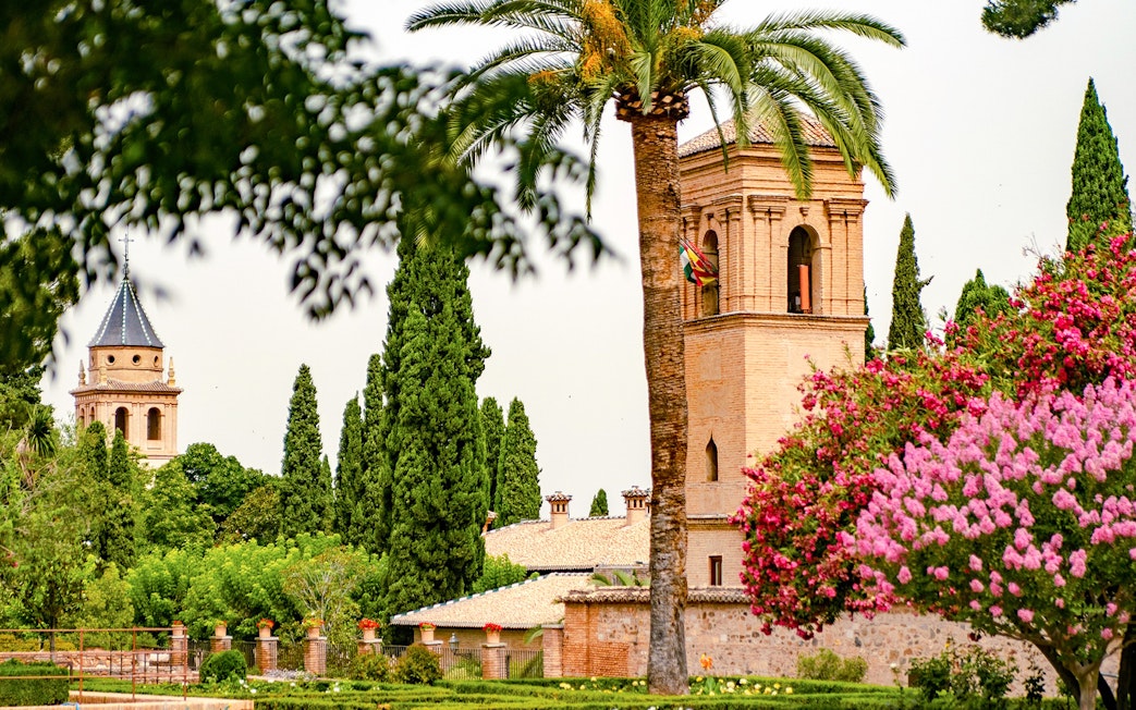 Generalife Gardens view with historic tower and lush greenery in Granada, Spain.
